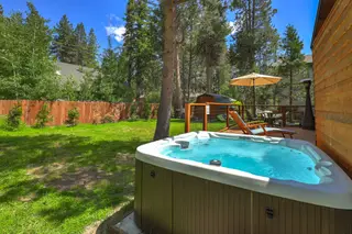 The hot tub, lawn and pines behind.